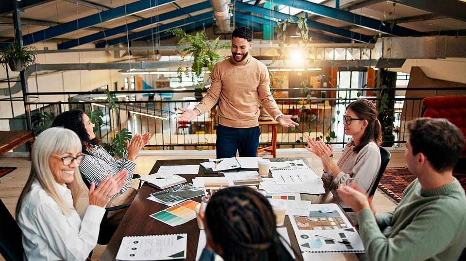 Project professionals in a conference room applauding a colleague's presentation.