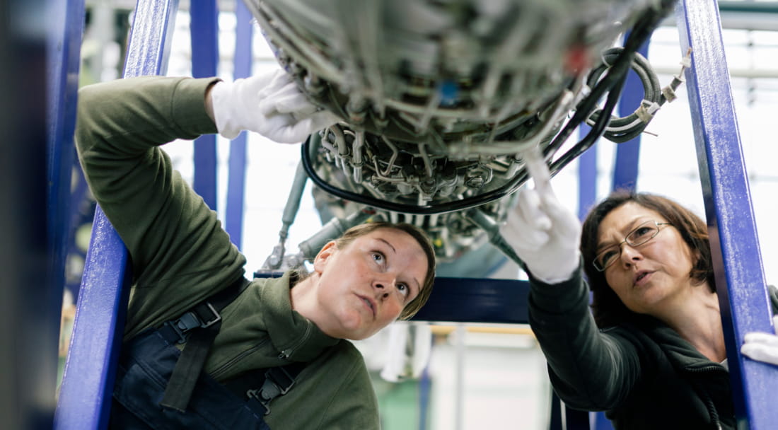 Two women looking and pointing up while working on a project