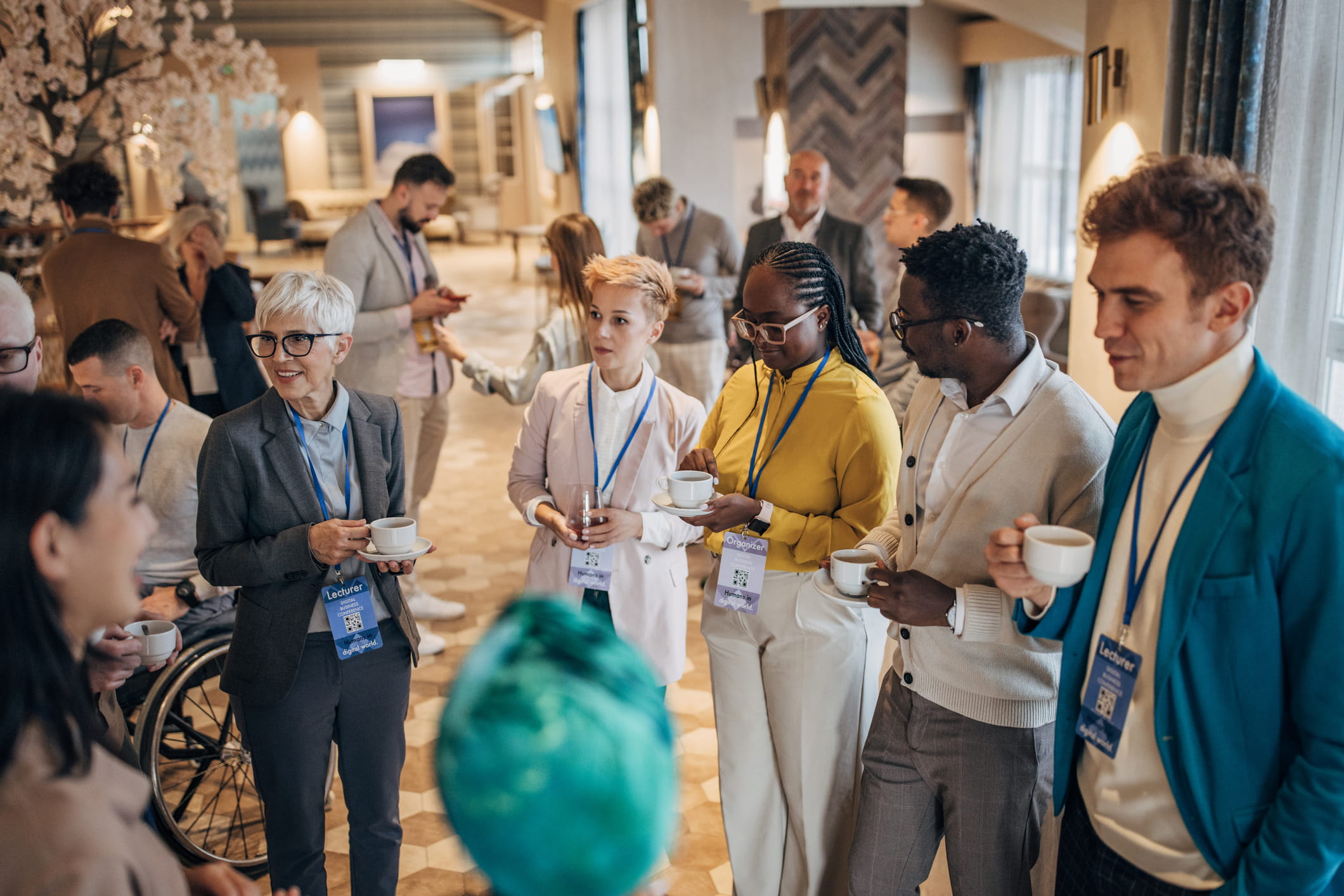 Group of people standing in a circle at a conference, holding coffee cups