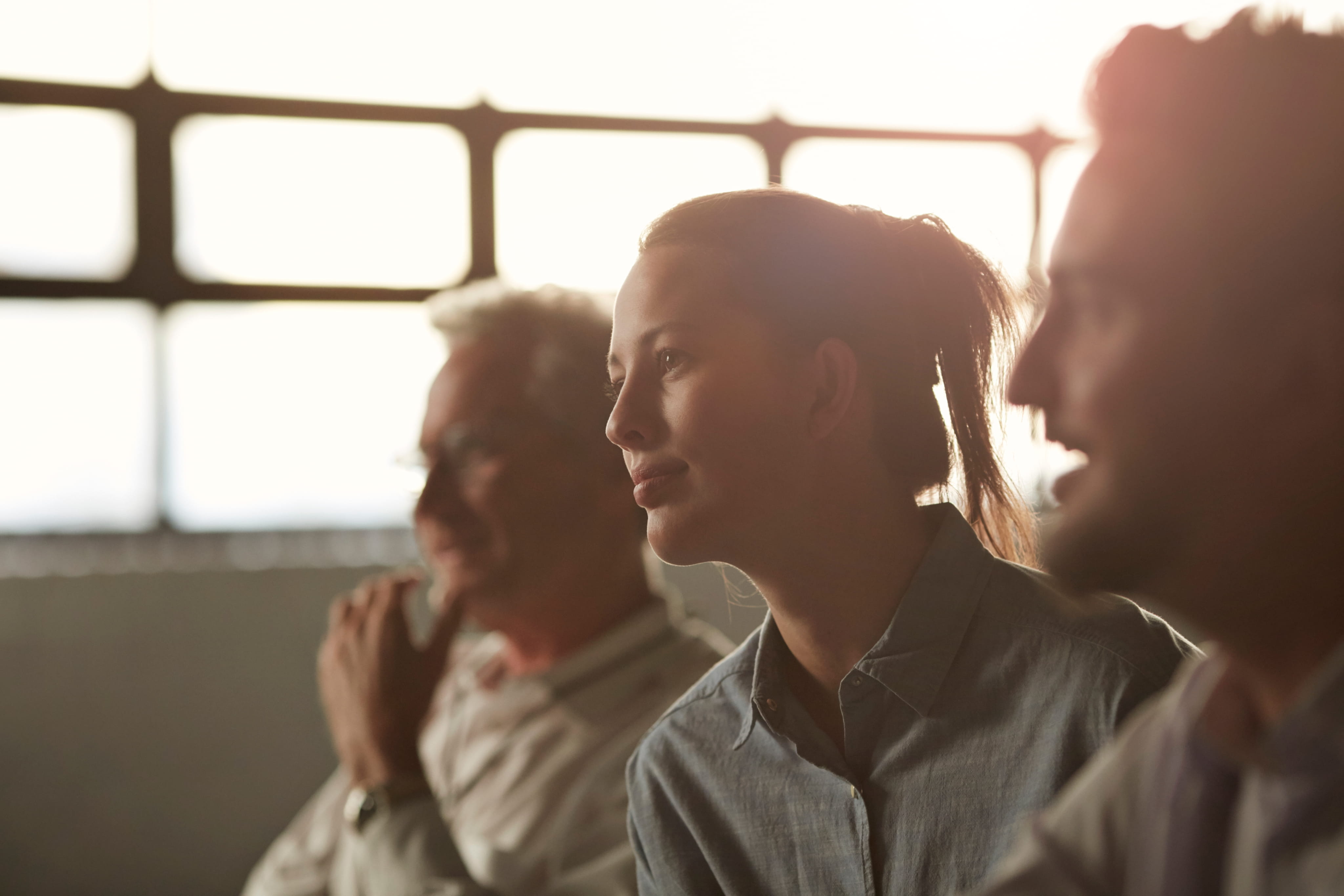 Three people sitting and facing forward, listening intently to someone