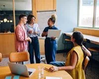 University faculty and students discuss project work around a table.