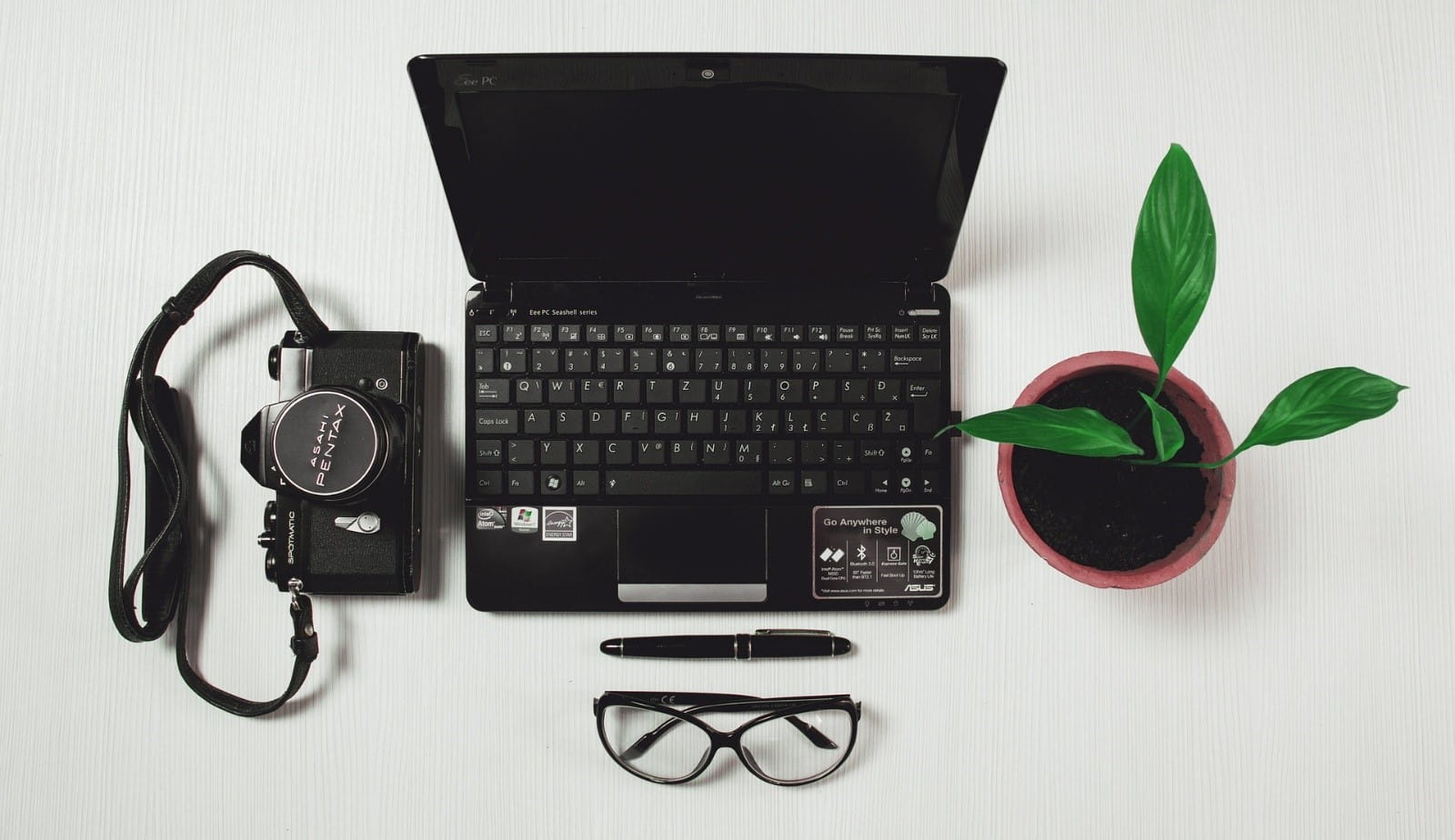 Stock photo top view of camera, laptop, plant in pot, glasses and pen