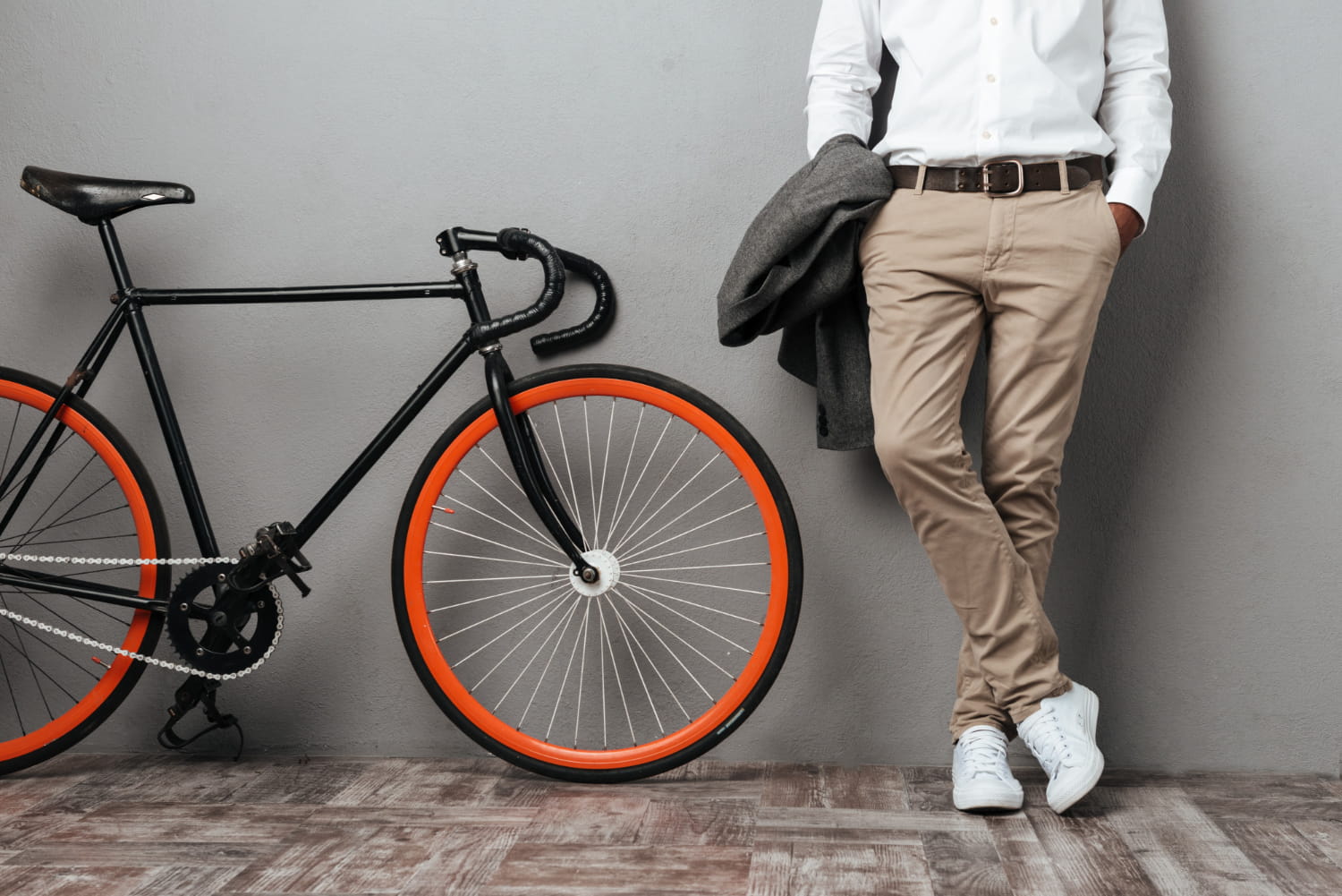 Person standing against a wall next to a bicycle