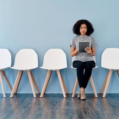 Woman sitting in an empty row of chairs